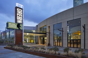 The exterior of OCC's main entrance featuring a large metal sign lit with "Oregon" and a digital sign at twilight. 