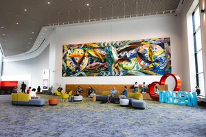 A painting of leaping fish hangs in a large building lobby.