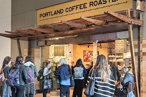 People gather under a wooden awning of a coffee shop. 
