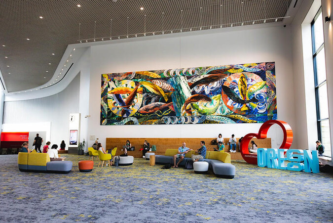 A painting of leaping fish hangs in a large building lobby.