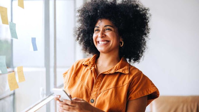 Smiling woman holds a phone.