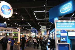 A bustling tech convention features booths from NASA and Intel, with attendees interacting. Bright, futuristic displays create an energetic atmosphere.