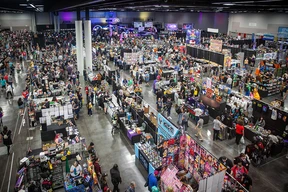 A bustling convention hall filled with colorful vendor booths and attendees browsing merchandise. Bright lights and displays create an energetic atmosphere.